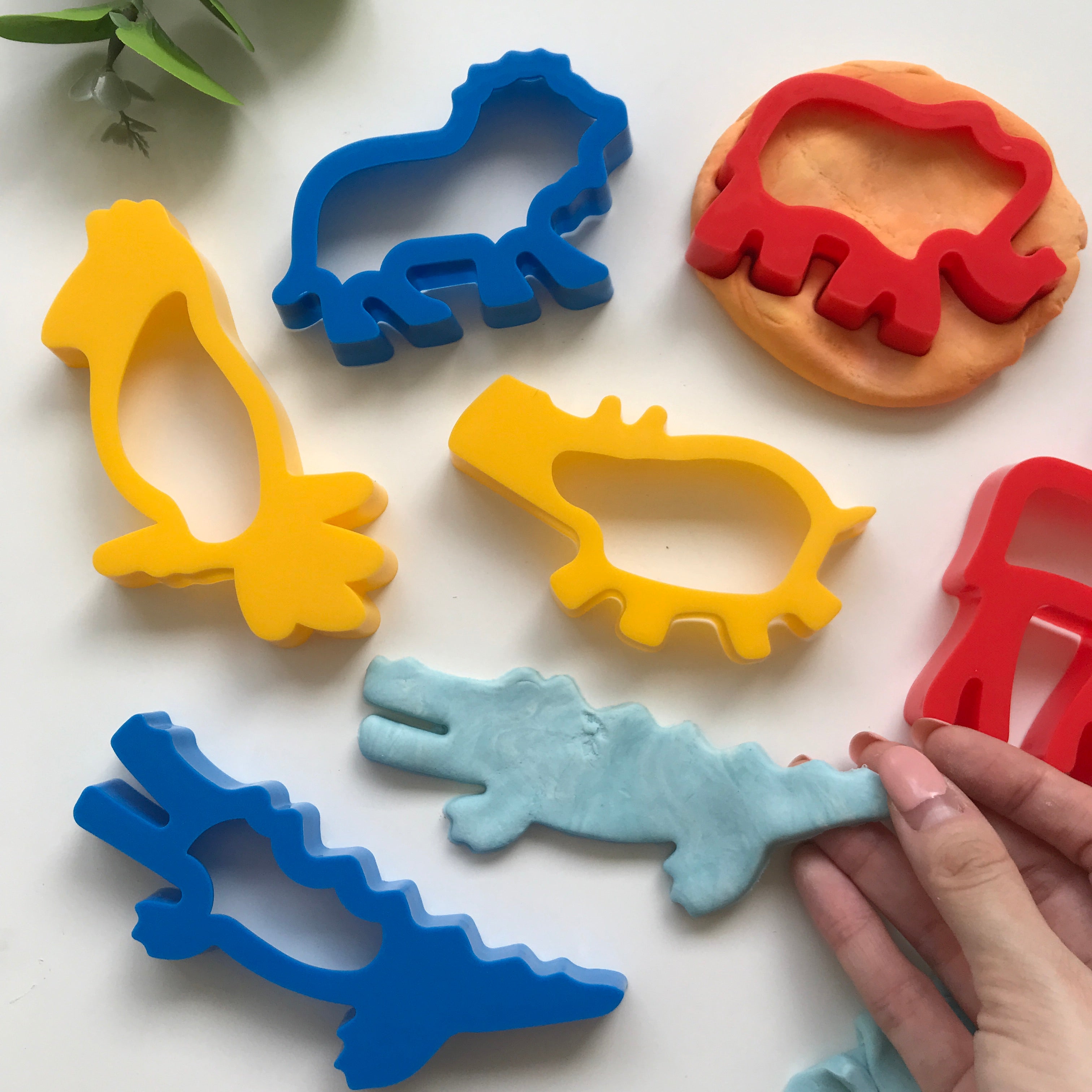 A set of six colorful plastic dough cutters in the shapes of jungle animals, including a hippo, elephant, lion, parrot, crocodile, and giraffe.