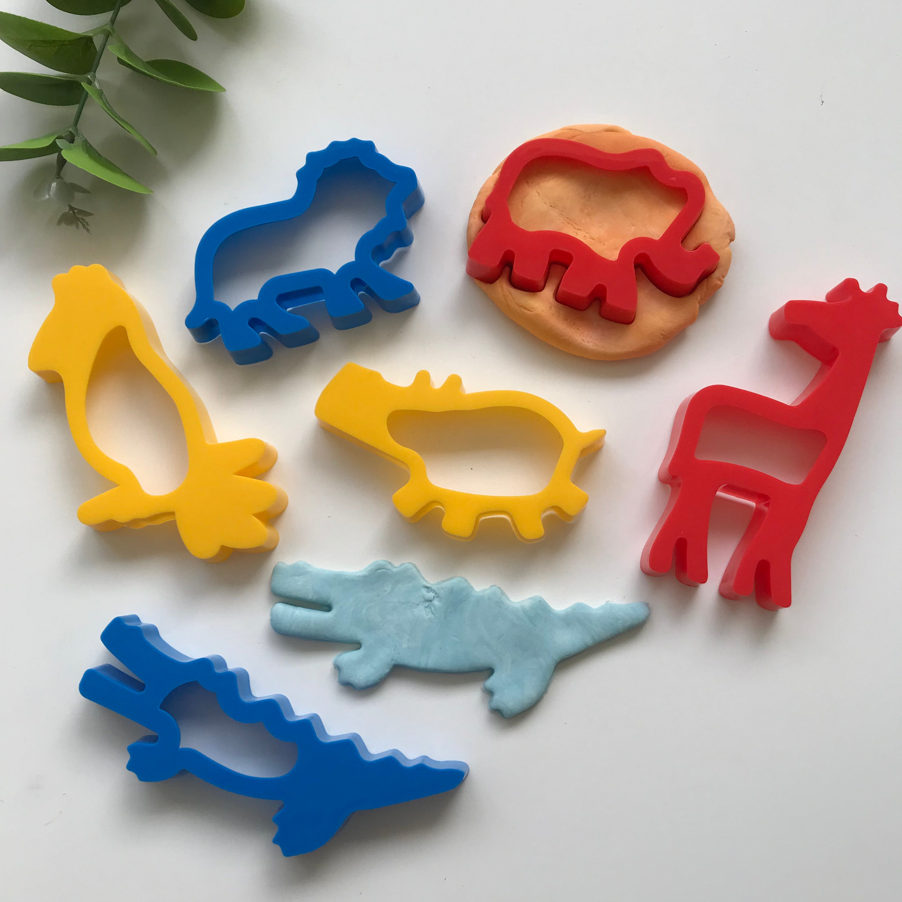 A set of six colorful plastic dough cutters in the shapes of jungle animals, including a hippo, elephant, lion, parrot, crocodile, and giraffe.