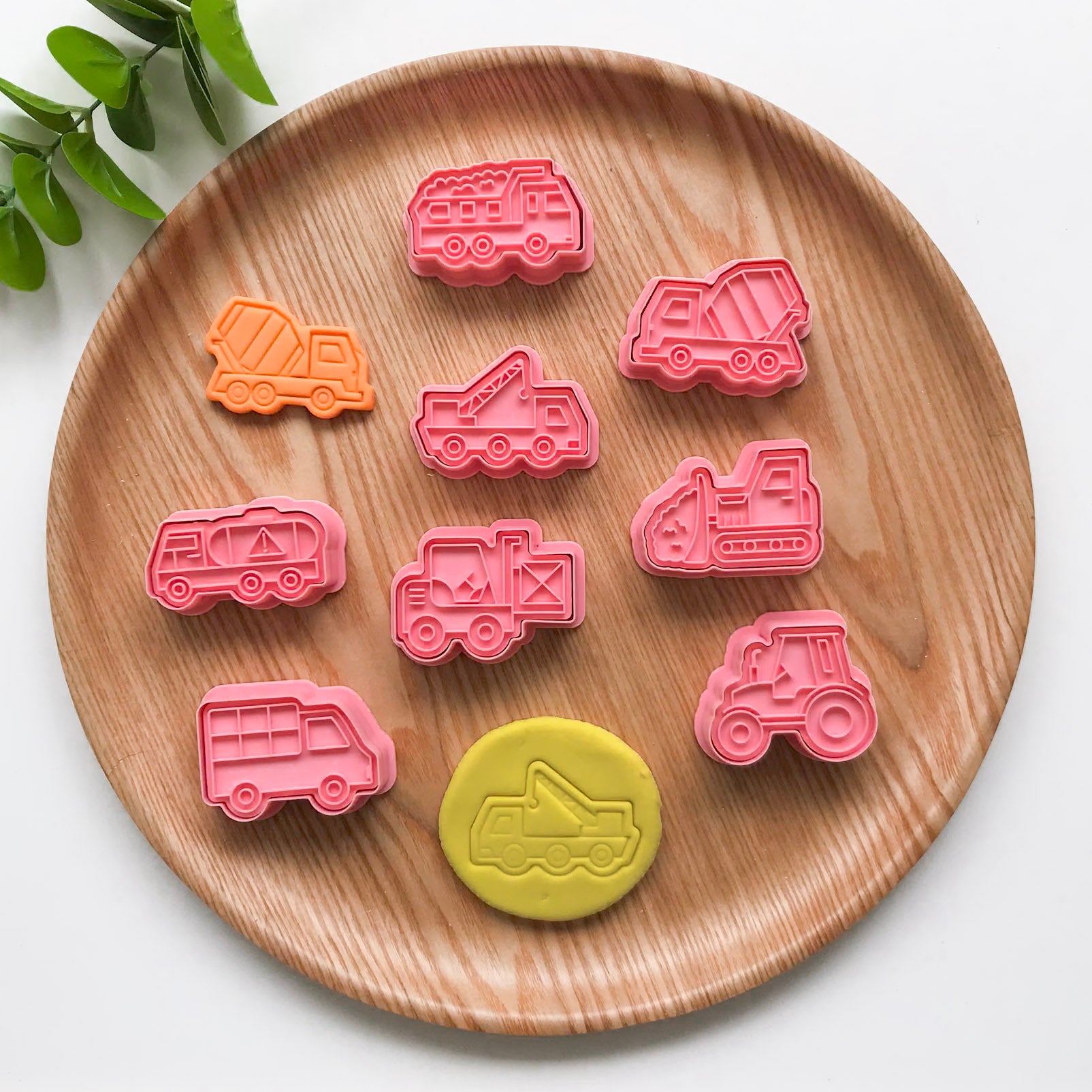 A set of 8 construction themed playdough cutters. They are displayed on a wooden plate