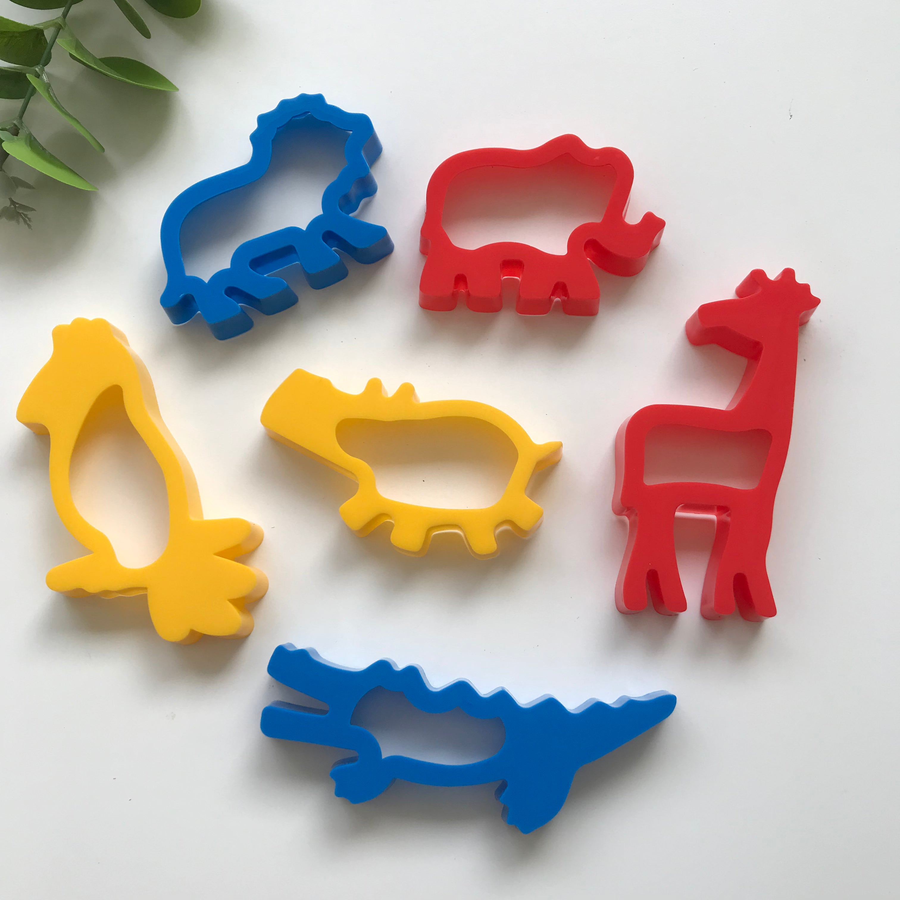 A set of six colorful plastic dough cutters in the shapes of jungle animals, including a hippo, elephant, lion, parrot, crocodile, and giraffe.