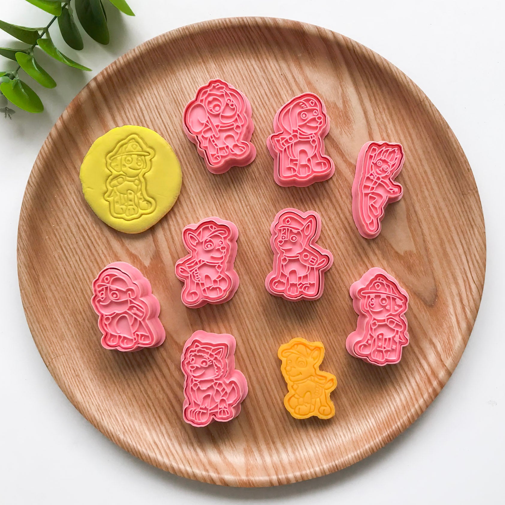 A set of colorful playdough utters and 8 different stamper designs with a cartoon puppy design, displayed on a wooden plate.