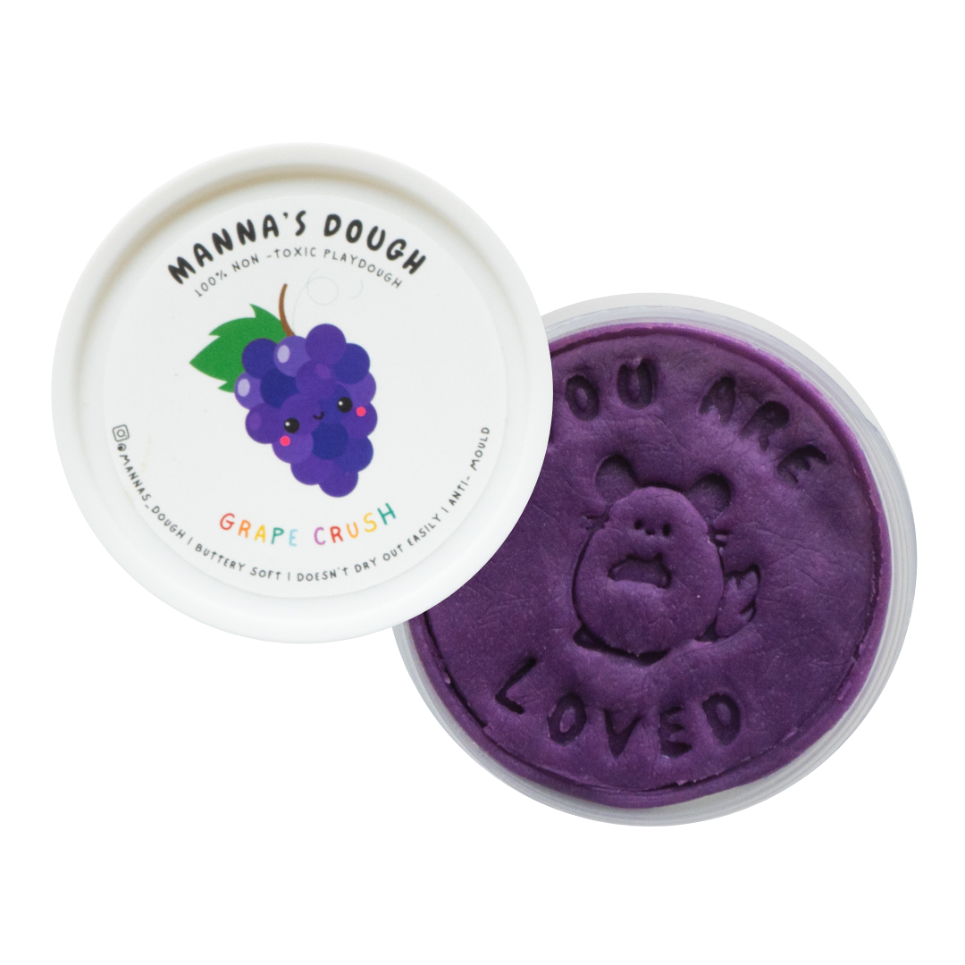A container of purple playdough with a lid featuring a grape design, and the text 'You are loved' on the playdough surface.