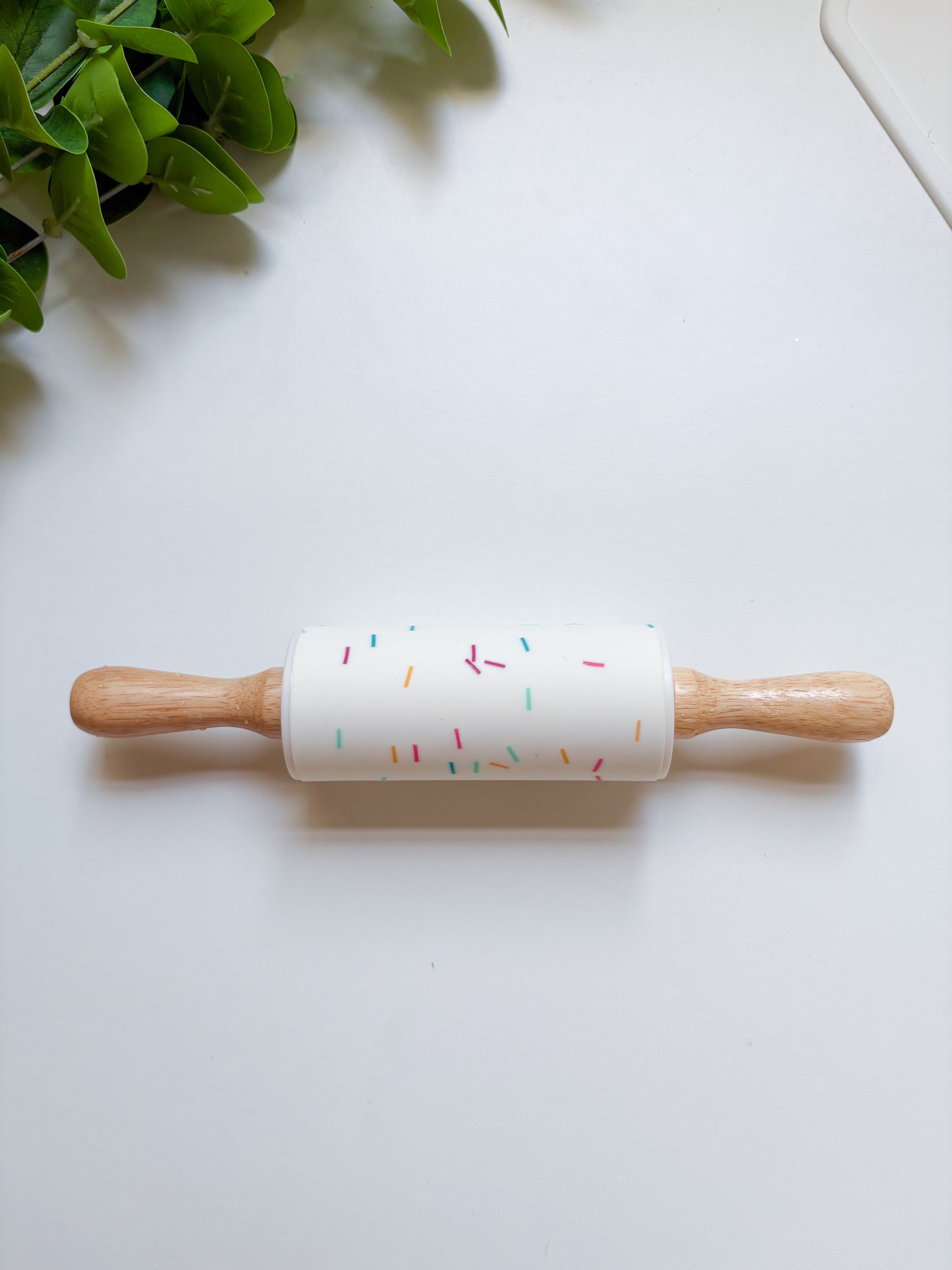 Rolling pin with colorful sprinkles design on a white surface