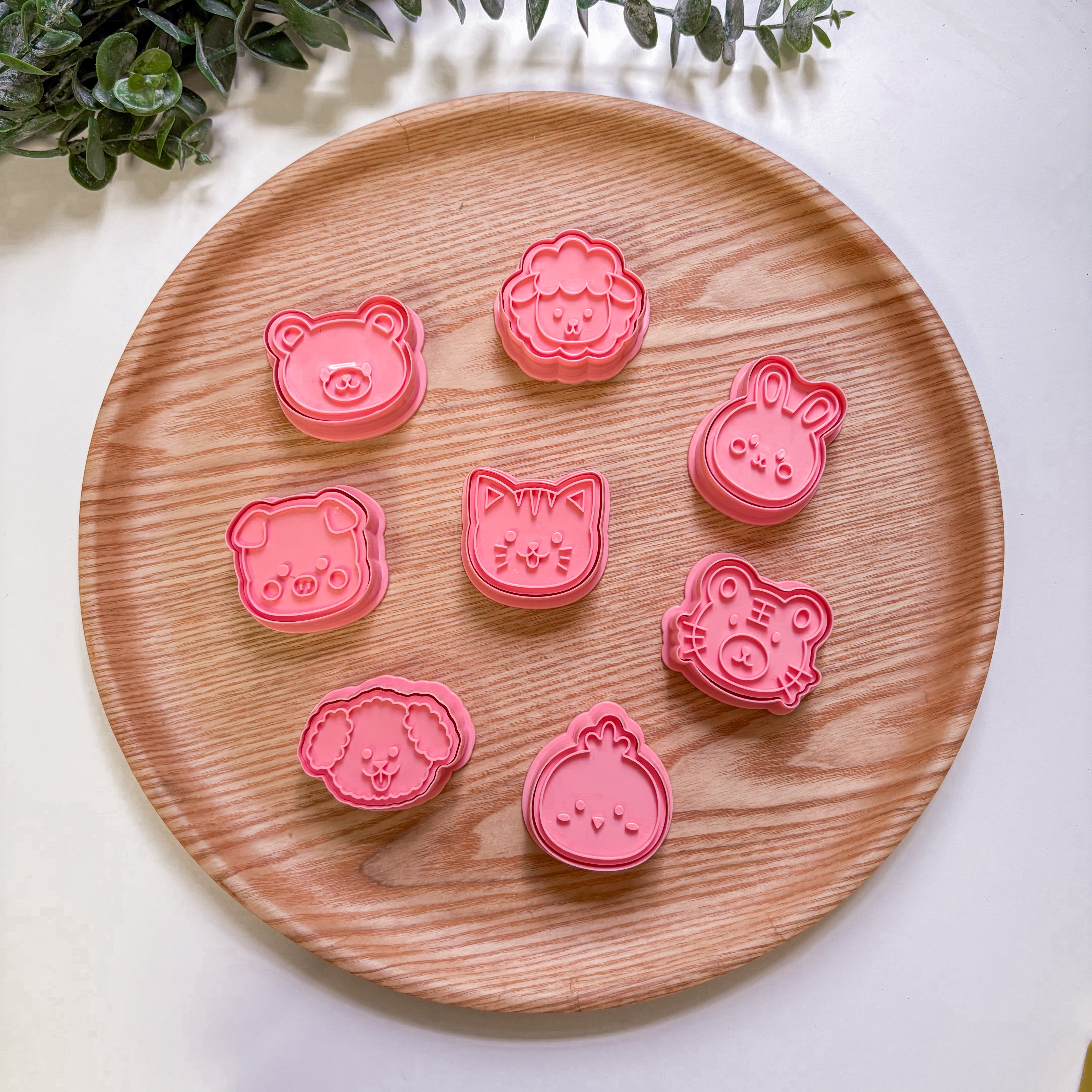 Set of pink animal-shaped cookie cutters on a wooden plate with a light background