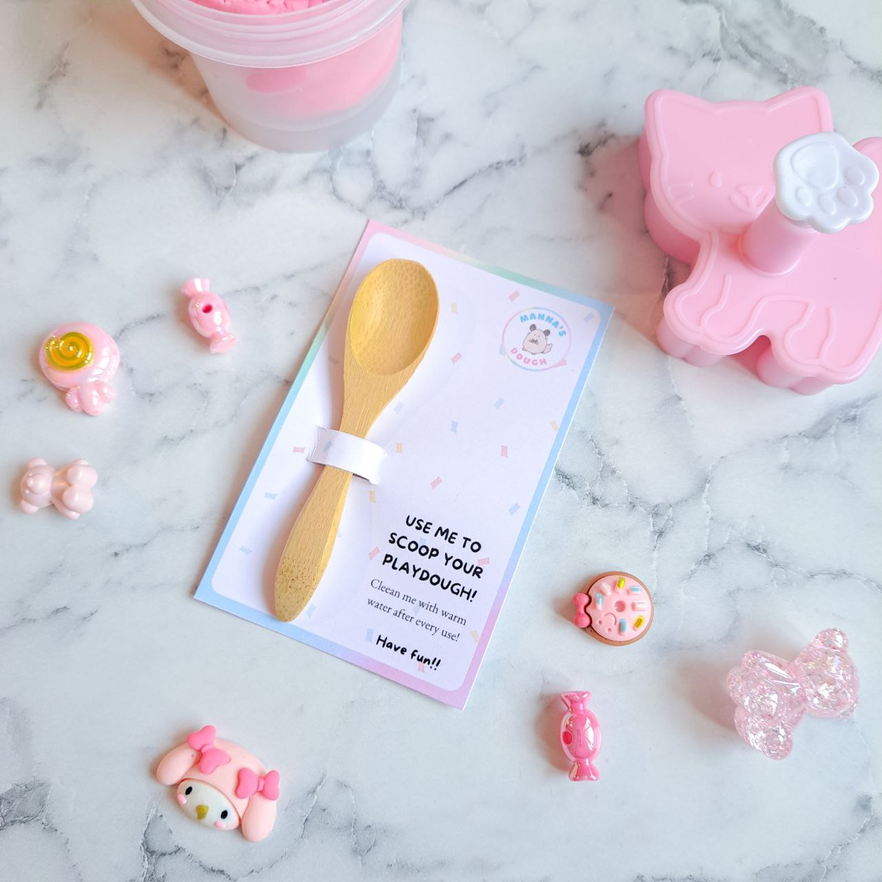 A wooden playdough scoop with a colorful backing