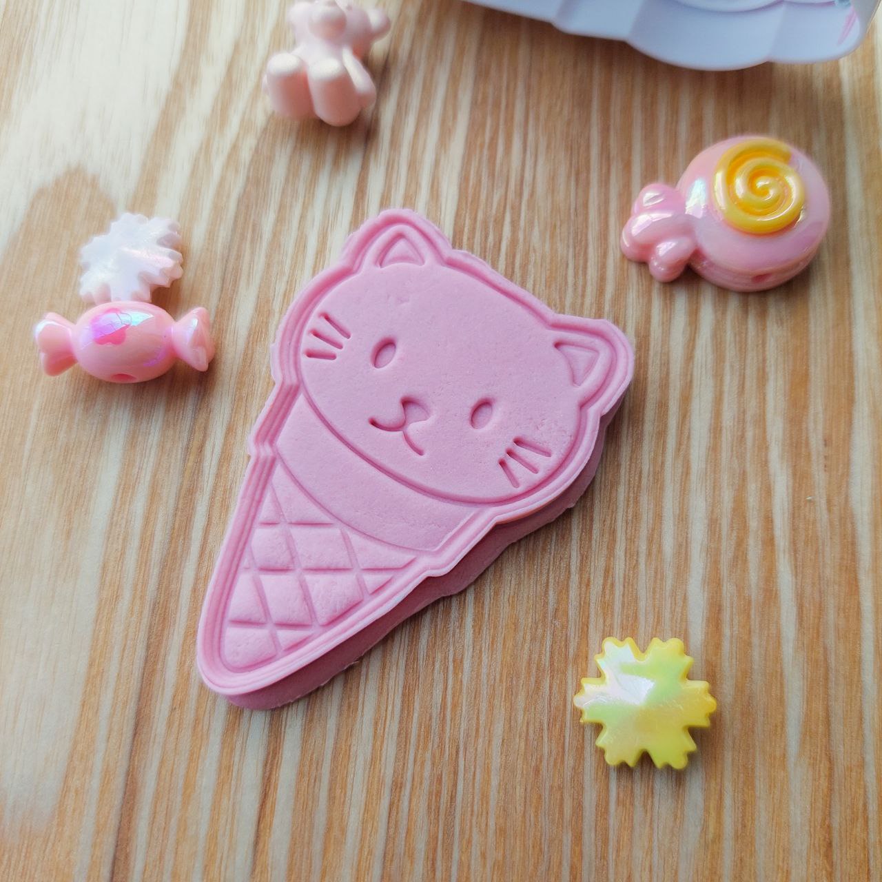 A pink color cat ice cream playdough cutout alongside with some playdough charms