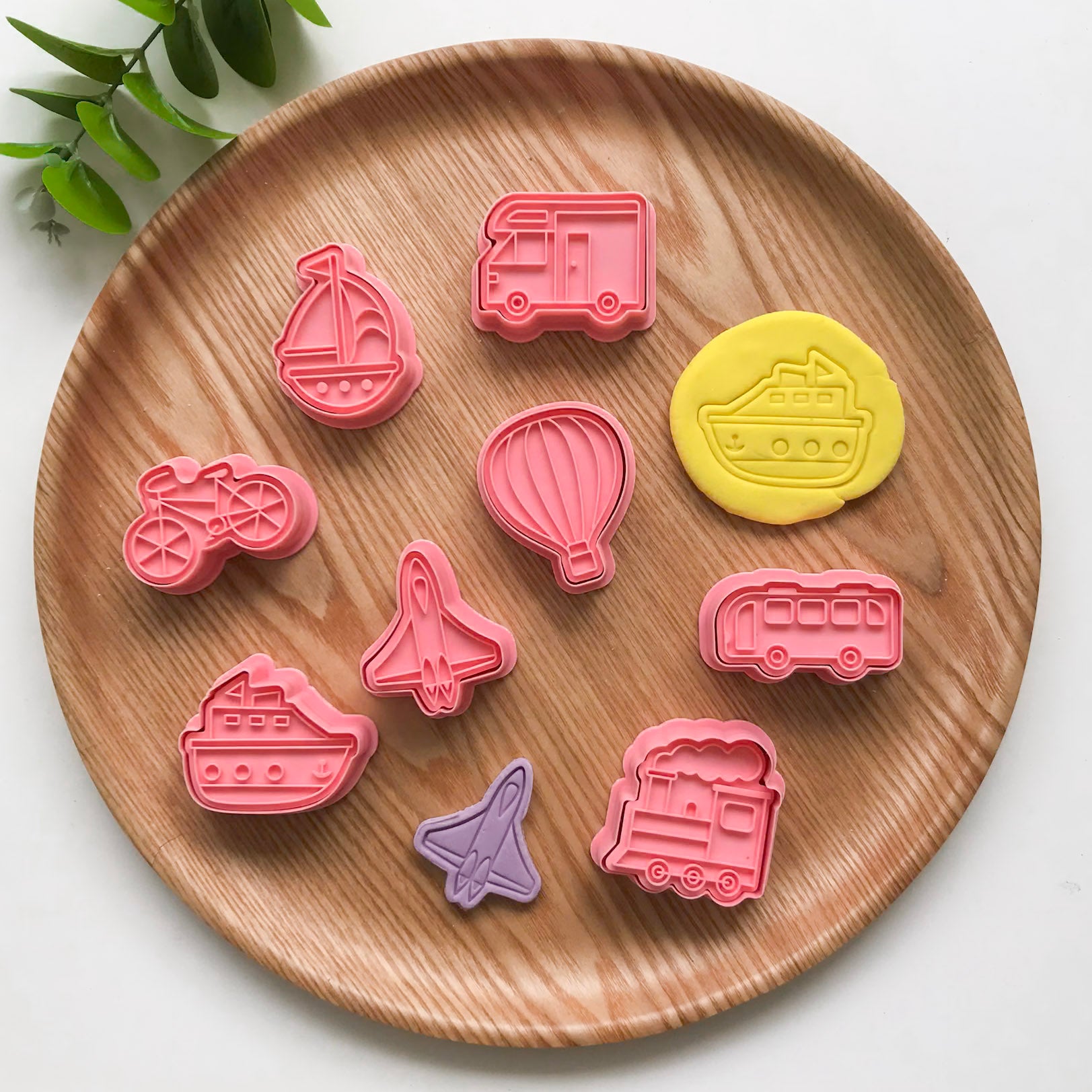 A set of 8 playdough vehicle themed cutters featuring a truck, boat, bicycle, ship, airplane, hot air balloon, train and bus. Alongside two playdough creations, a yellow ship and a purple planea
