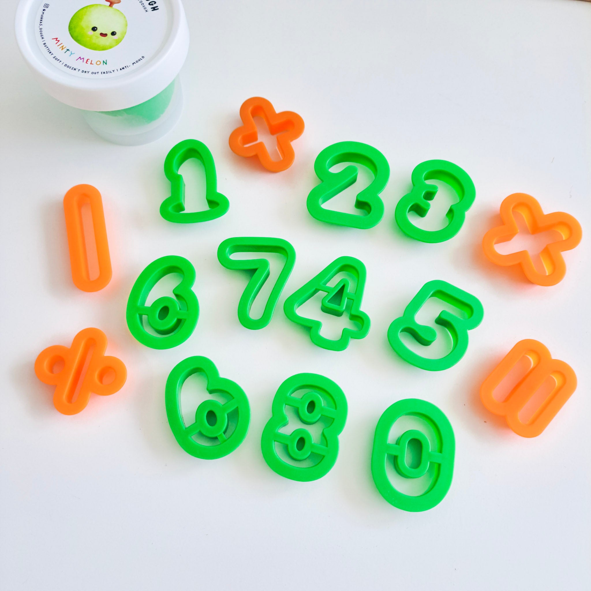 A set of brightly colored plastic cutters shaped like numbers 0-9 and math symbols, designed for use with playdough or for baking.