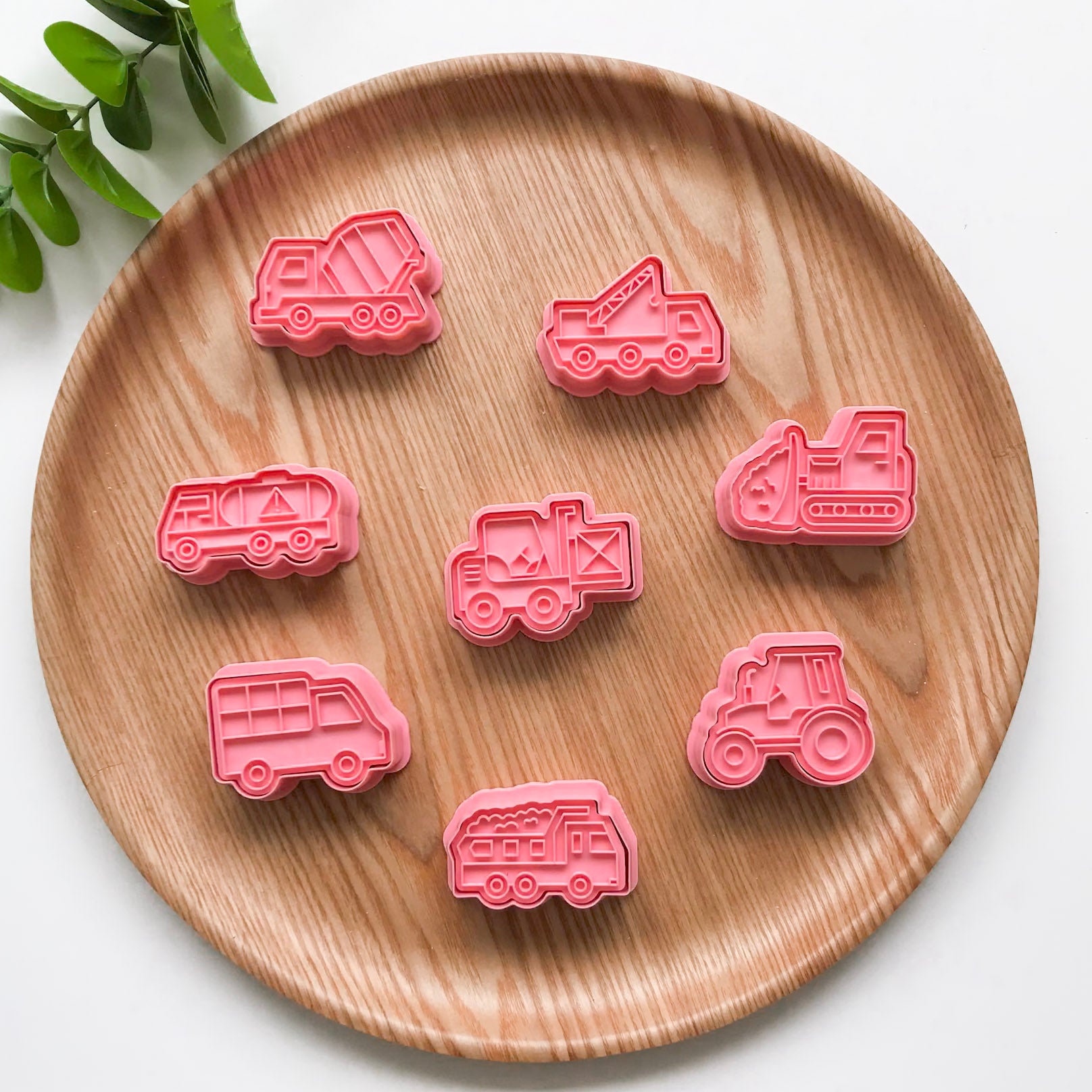 A set of 8 construction themed playdough cutters. They are displayed on a wooden plate