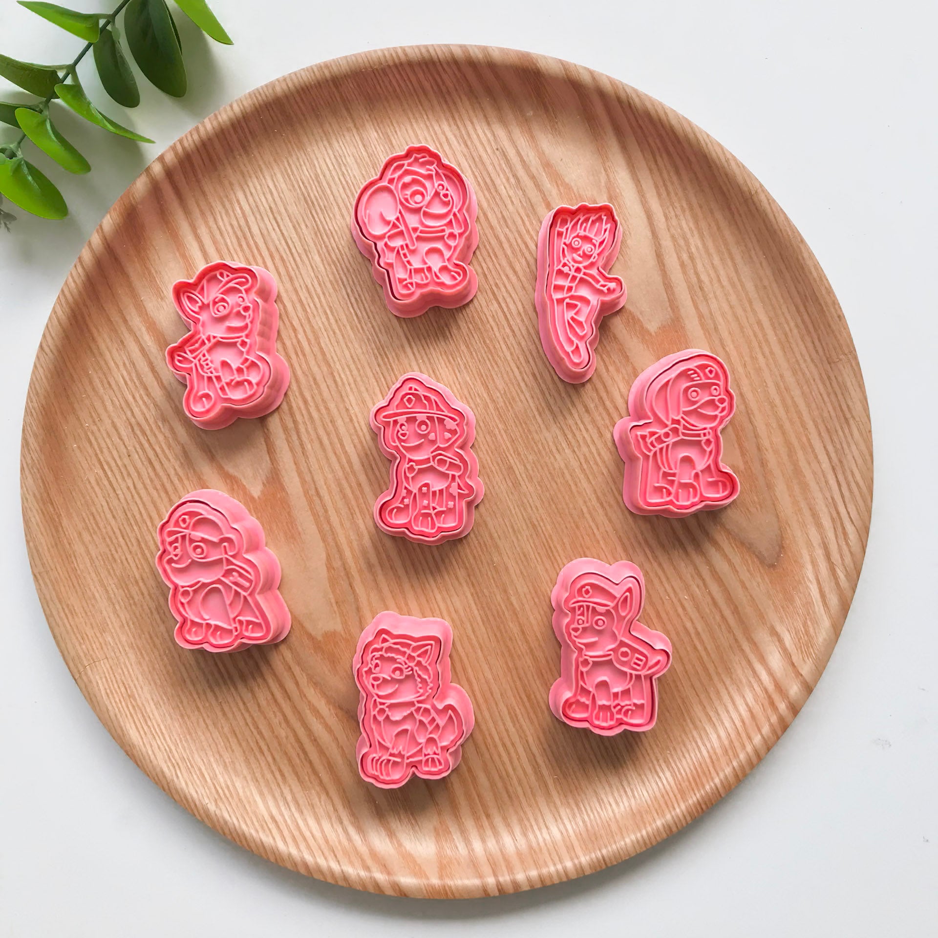 A set of colorful playdough utters and 8 different stamper designs with a cartoon puppy design, displayed on a wooden plate.