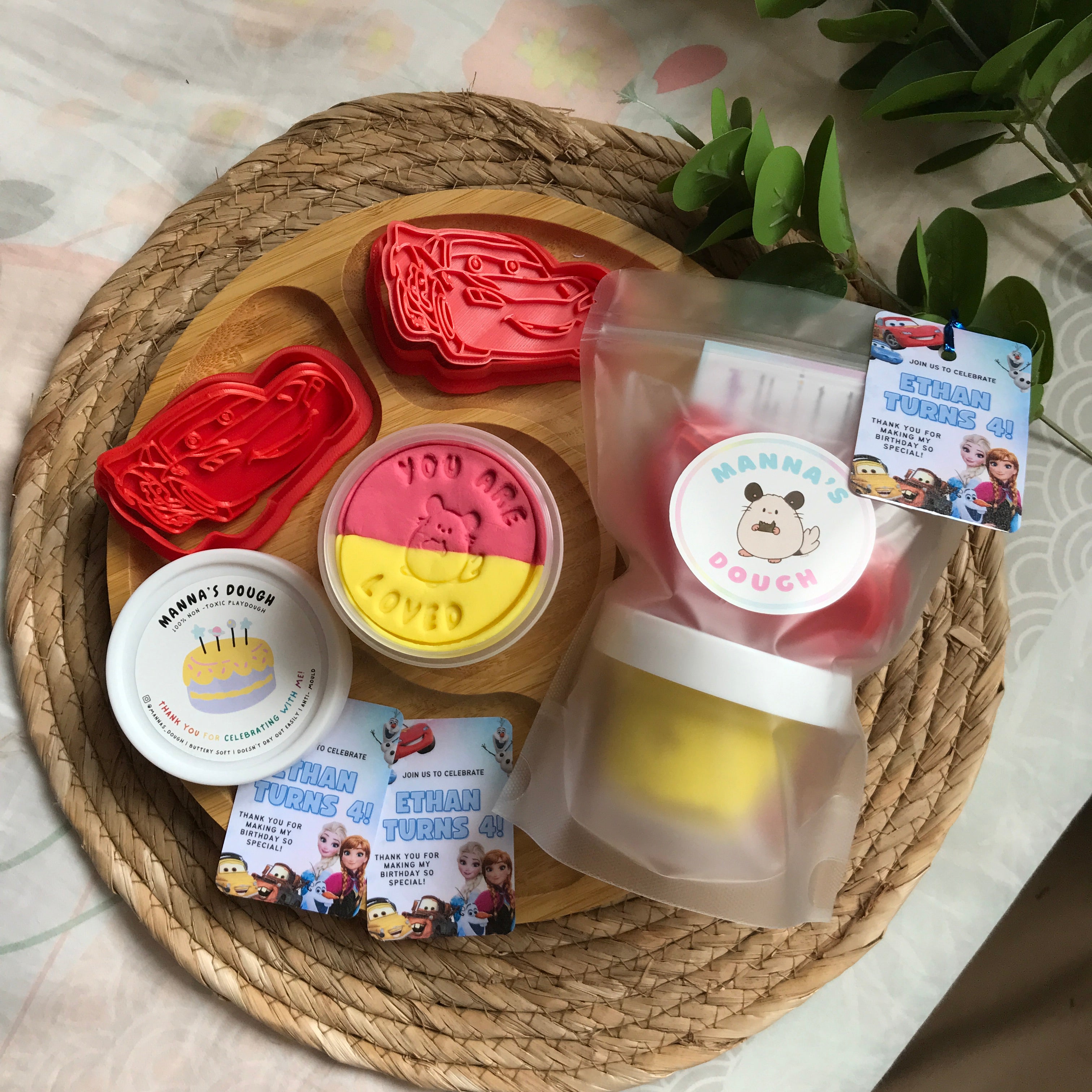 A playdough party pack featuring a Lightning McQueen themed stamper, dual-colored red and yellow playdough, and a themed gift tag.