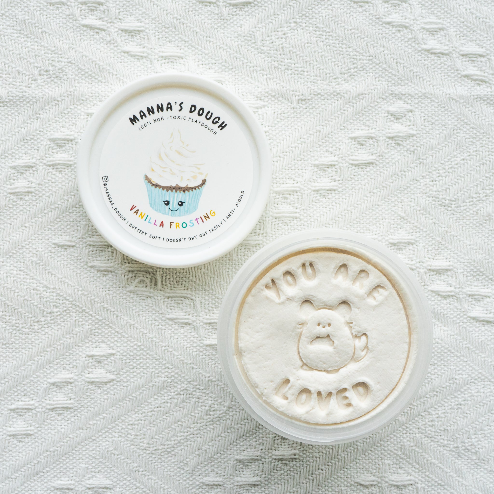 A pot of white playdough with a cupcake design and the text 'You are loved' on the lid.